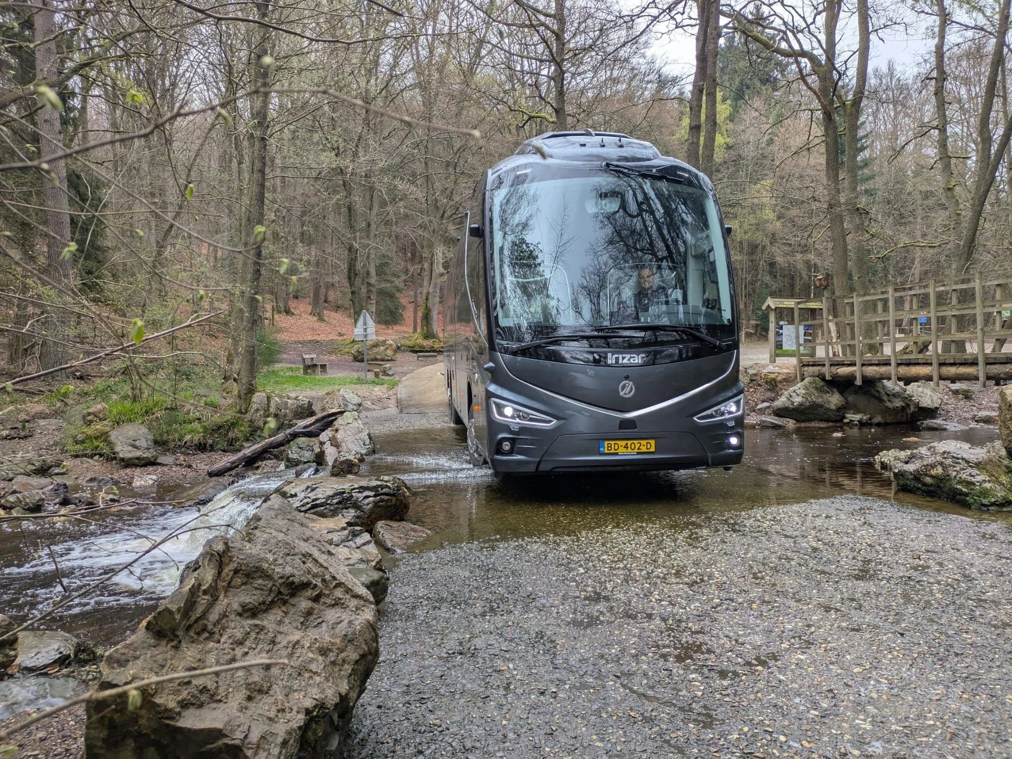 Touringcar van Hofman Personenvervoer in een bosrijke omgeving