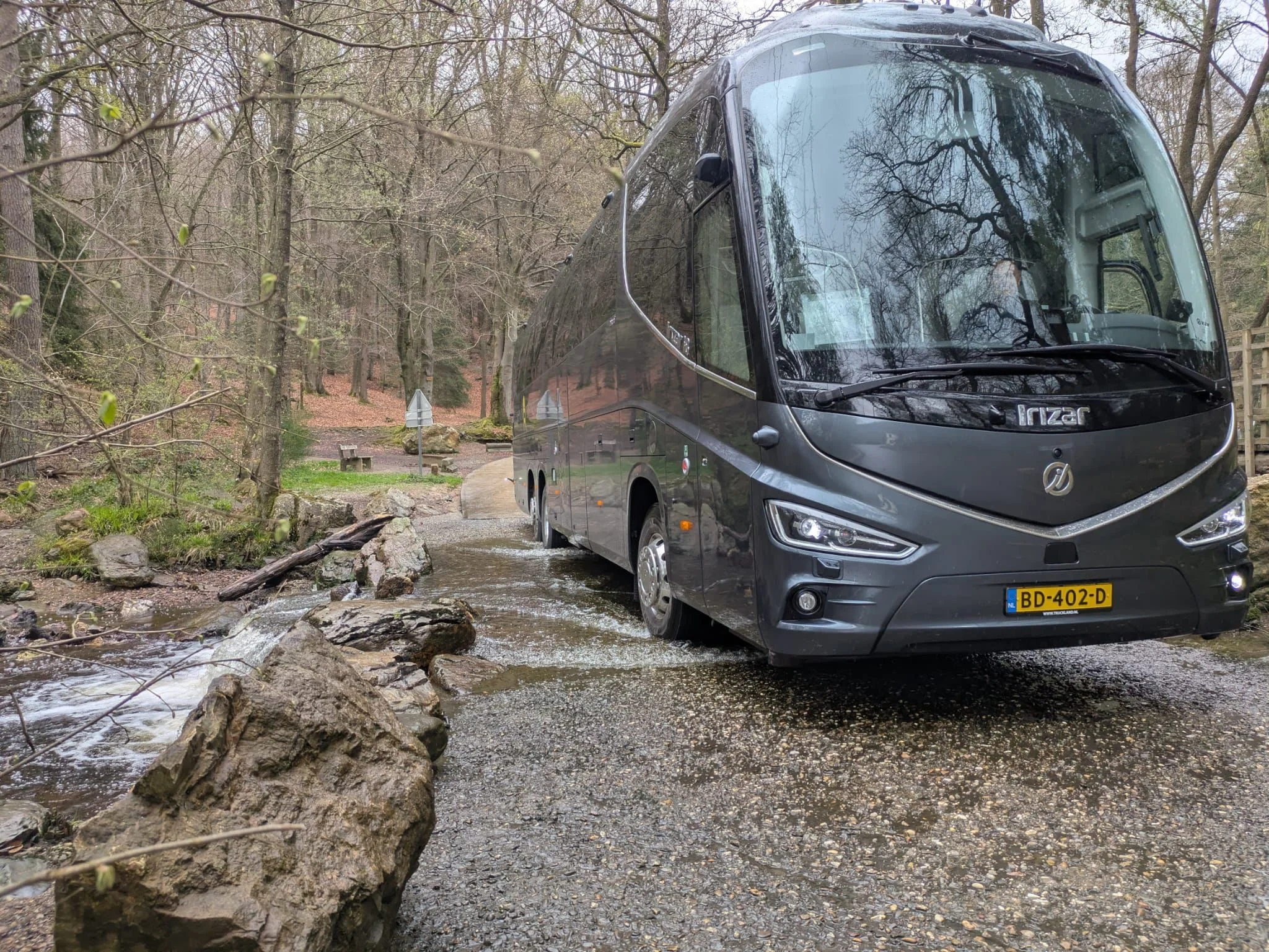 Touringcar van Hofman Personenvervoer in een bosrijke omgeving